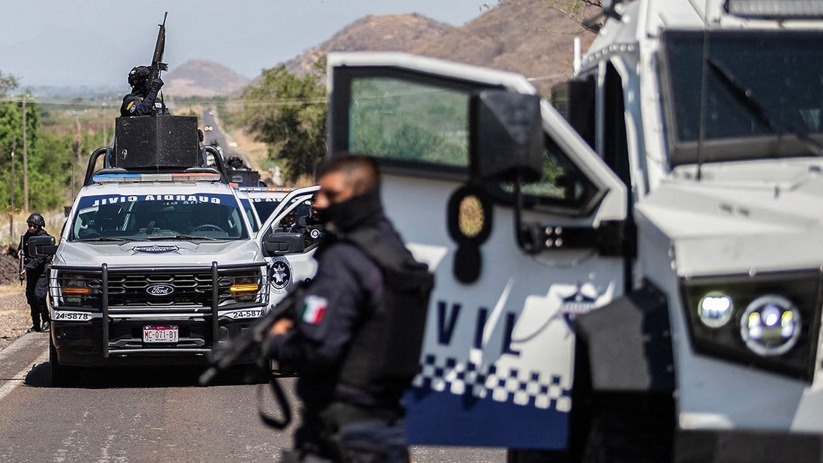 Civil Guard members of Michoacan patrol a highway in armored vehicles.