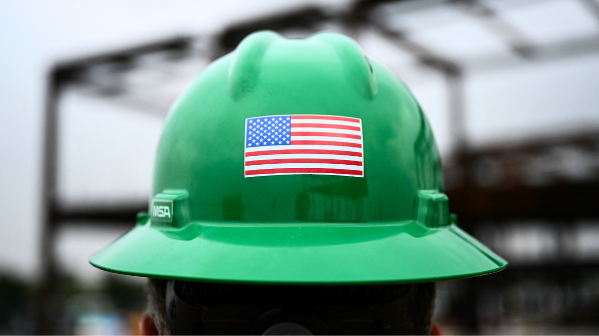 A person is seen wearing a hard hat with an American flag sticker on it.