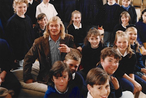 John Farnham, circa 1990, visiting an Australian Children’s Choir rehearsal, with Kate Howard, behind his shoulder at left, and Sascha Davis behind his shoulder at right. Kate’s sister Nicole is sitting to the right of Farnham.