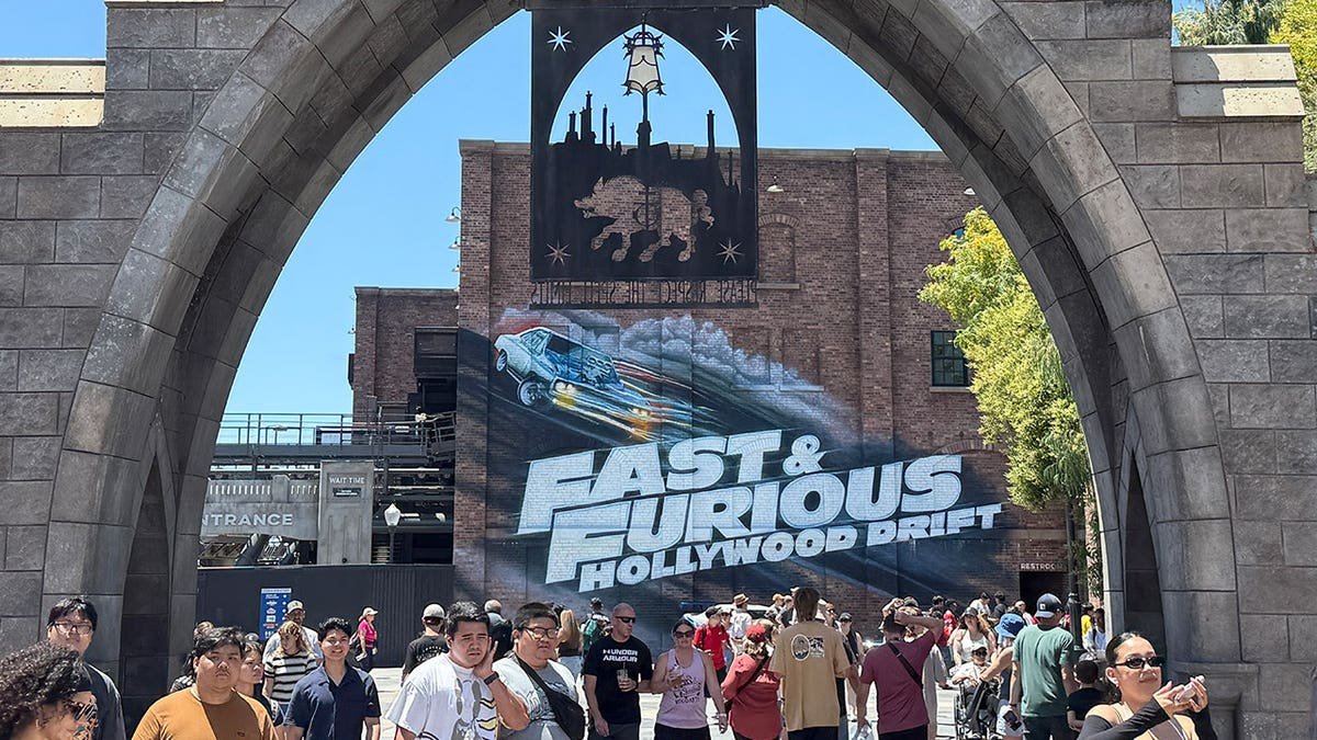 People stand near the Fast & Furious: Hollywood Drift roller coaster at Universal Studios Hollywood.