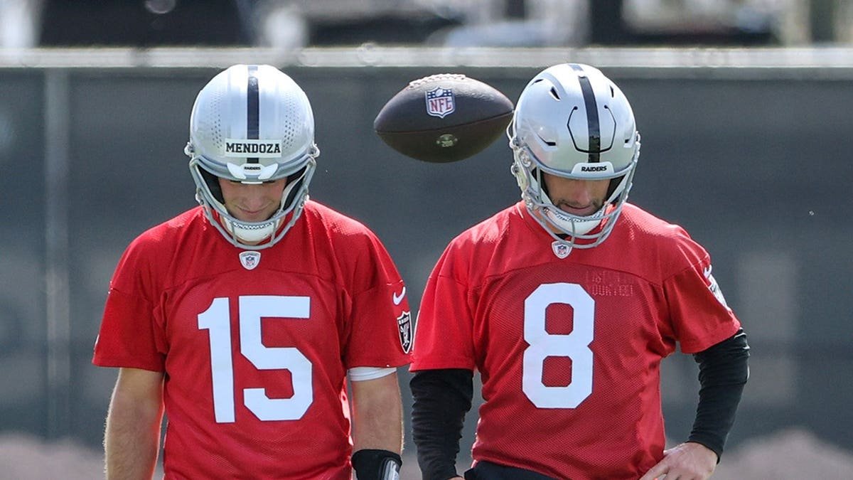Fernando Mendoza and Kirk Cousins walk on a field during a Las Vegas Raiders OTA workout.
