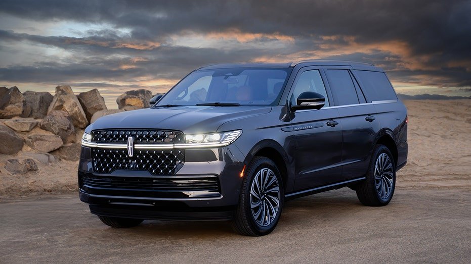A Lincoln Navigator SUV is displayed against a desert backdrop at sunset.