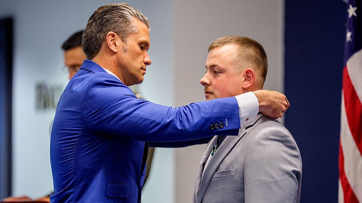 Secretary of War Pete Hegseth puts a medal on Marine Cpl. Michael Gretzon during an event to honor Marines, who were serving during the 2021 Abbey Gate bombing, at the Pentagon, Wednesday, in Arlington, Va.