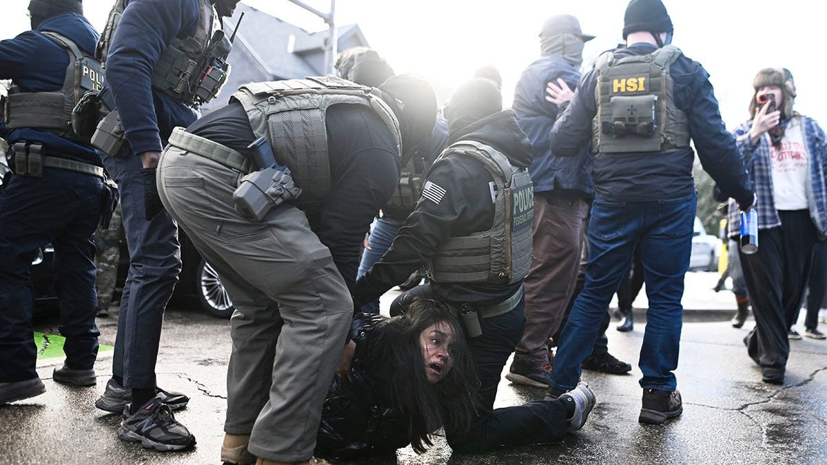 ICE agents detain a woman after pulling her from a car before on January 13, 2026, in Minneapolis, Minnesota. The Trump administration has deployed over 2,400 Department of Homeland Security agents to the state of Minnesota in a push to apprehend undocumented immigrants.