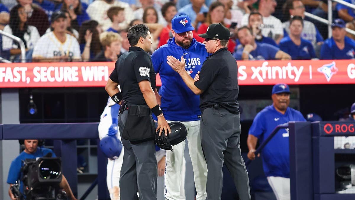 John Schneider stands with umpires during a rule review at Rogers Centre.