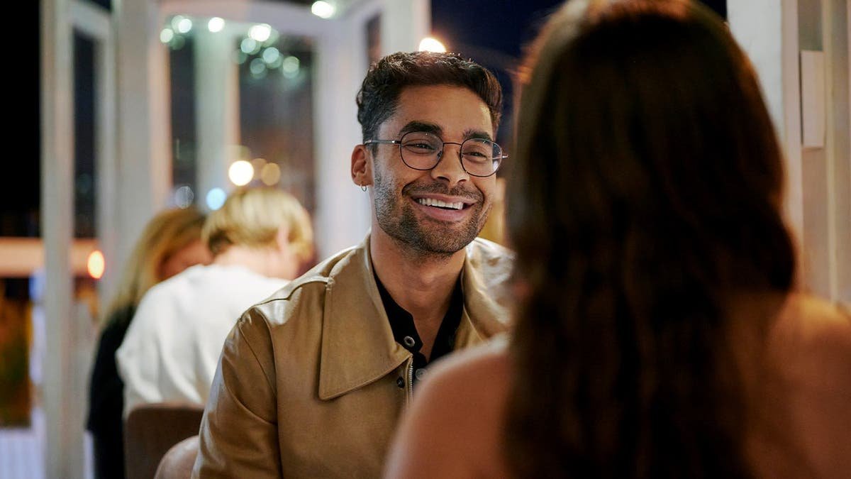 A young man laughs while on a date.