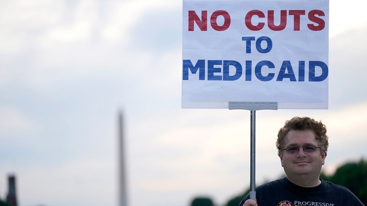 A protestor holds a sign at protect Medicaid lights up Capitol amid budget showdown, on May 07, 2025 in Washington, DC.