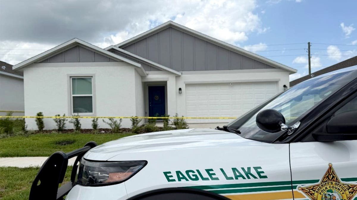 The exterior of a house is shown with a sheriff's car parked out front.