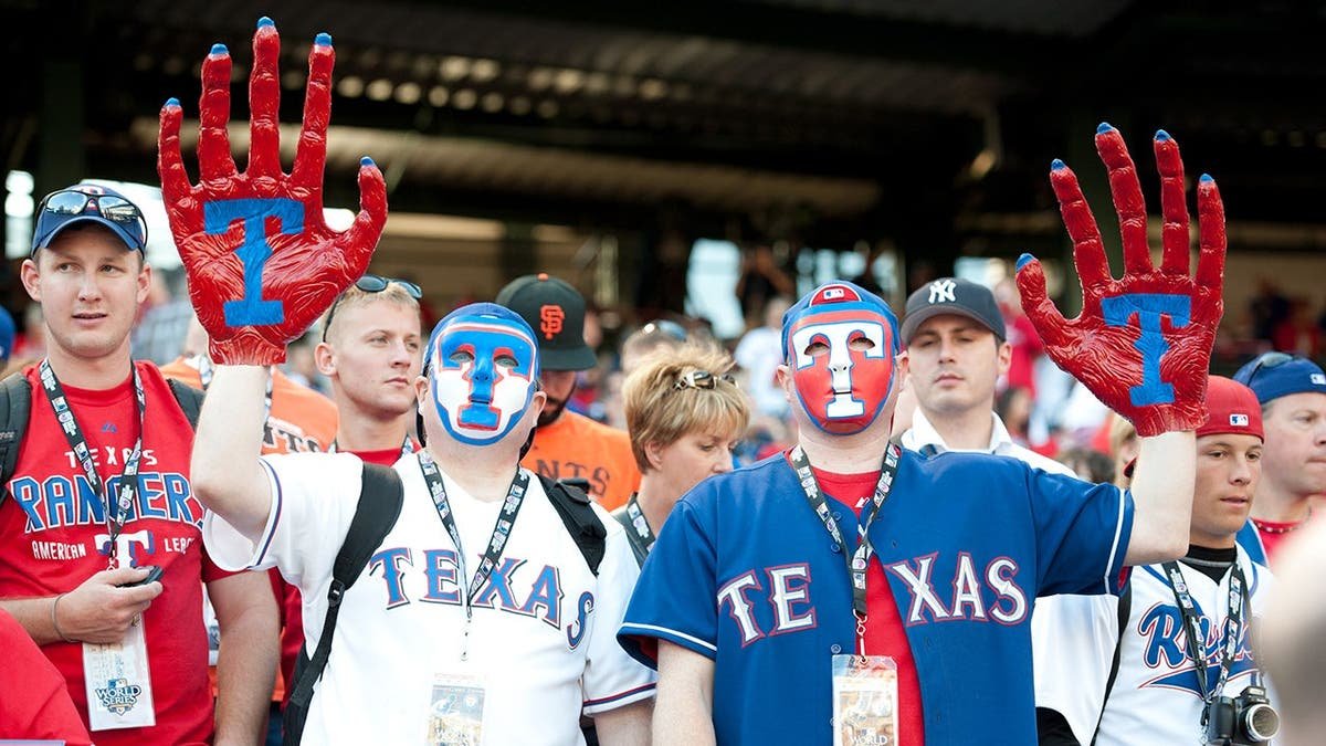 Texas Rangers fans hold large claws in the stands at Rangers Ballpark.