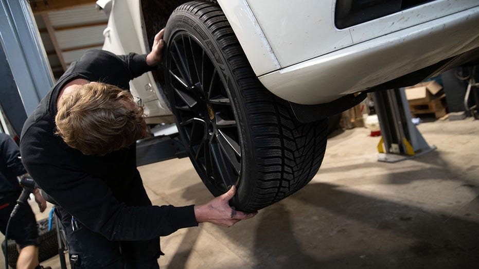 Mechanic fitting a wheel on a car during tire change.