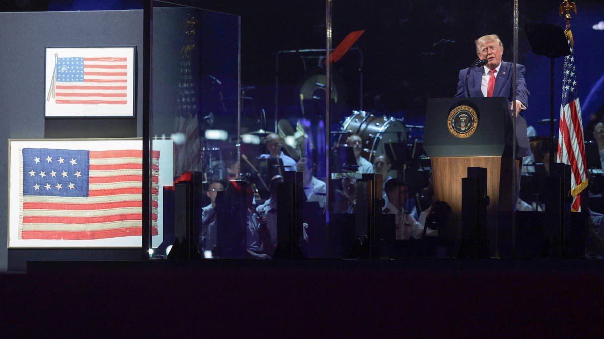Donald Trump speaks beside historic American flags during Fourth of July celebrations.