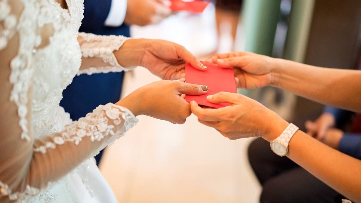 A bride receives an envelope from a guest at her wedding.