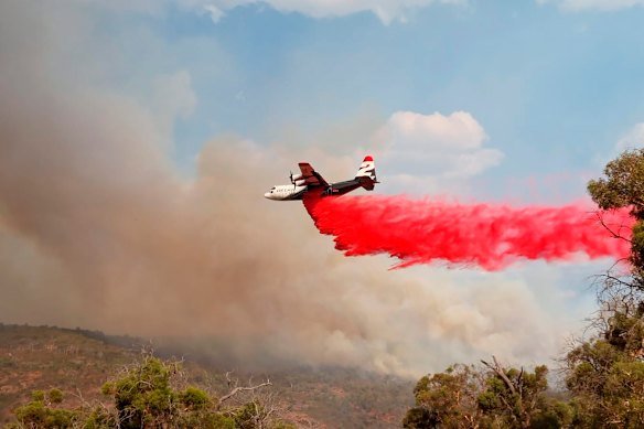 A firefighting plane dumps retardant on Wooroloo blaze.