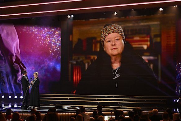 Magda Szubanski accepts her Logie Hall of Fame Award in 2025 via video link, with David Campbell and Marg Downey on stage.