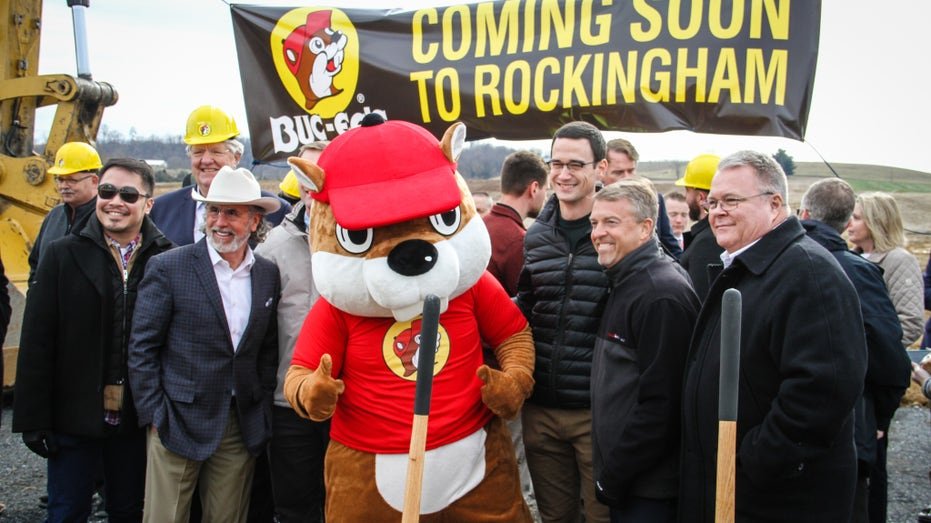 City officials standing next to Buc-ee's beaver mascot for photo at new construction location