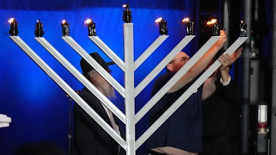 The father of 10-year-old Matilda, who died in the Bondi shootings, lights a candle on a menorah.
