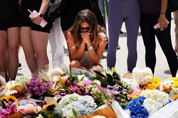 A woman prays at a flower memorial outside the Bondi Pavilion the day after the shootings. 