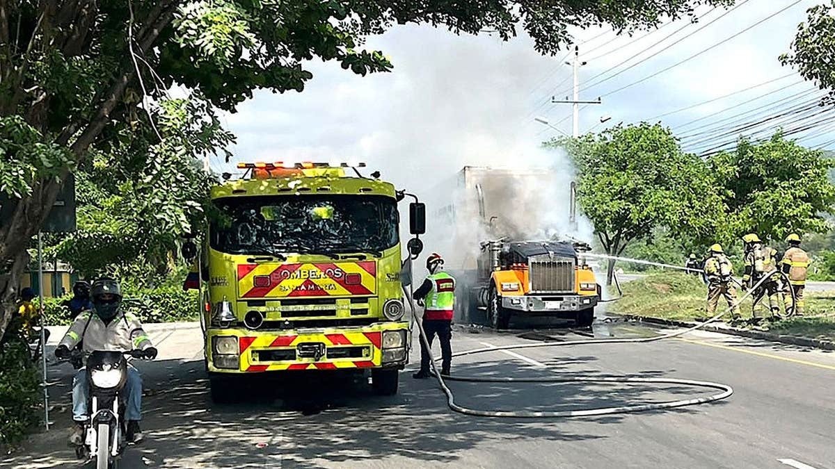 Firefighters extinguish a fire in a burnt truck following a military operation by the Colombian Army against the drug-related armed group Conquering Self Defense Forces of the Sierra Nevada (ACSN) in Santa Marta, Colombia
