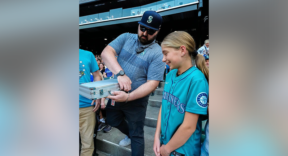 Mariners fan Abby watches as the one-of-one Jimothy rookie card is revealed at T-Mobile Park