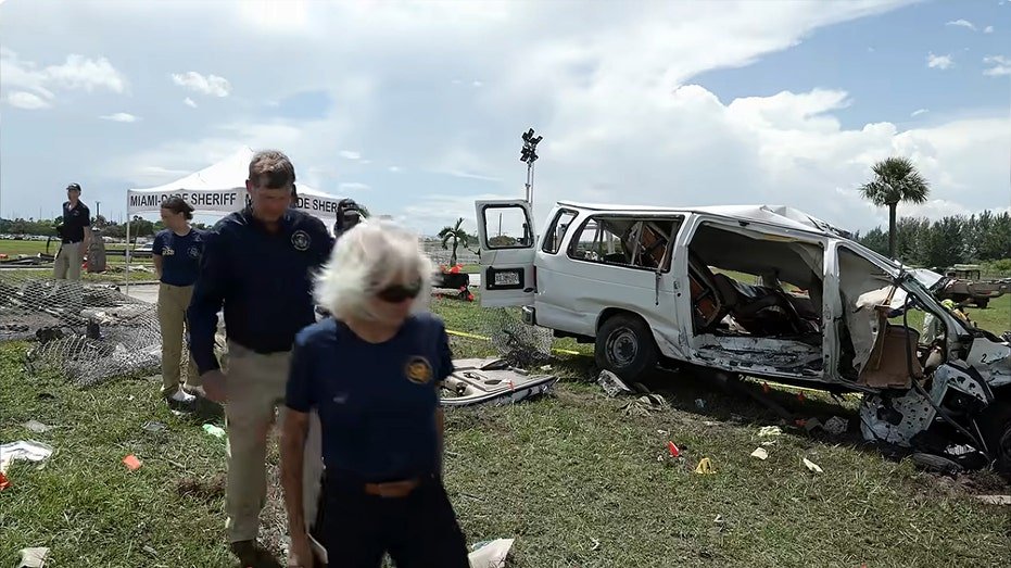 Officials walk near crushed van.