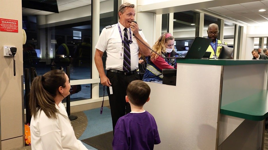 An Avelo Airlines worker addresses passengers at a gate before a flight.