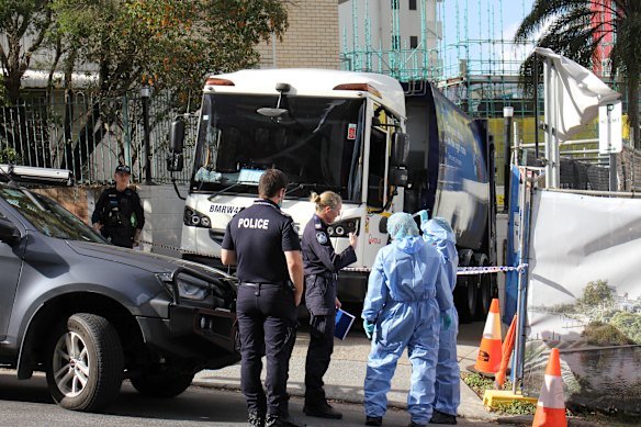 Forensic officers wearing blue suits enter the car park on Lambert Street in Kangaroo Point after the body was found.