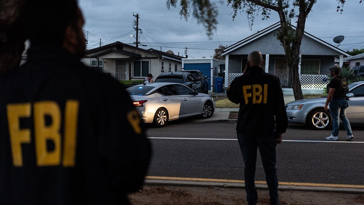 FBI agents stand outside a home in Los Angeles where Lakiya Malone is charged with fraud.