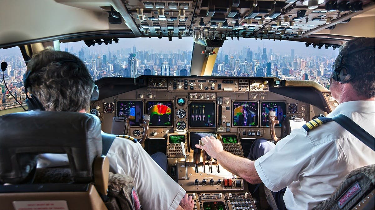 Cockpit of a modern passenger aircraft in flight with a view of city skyscrapers.