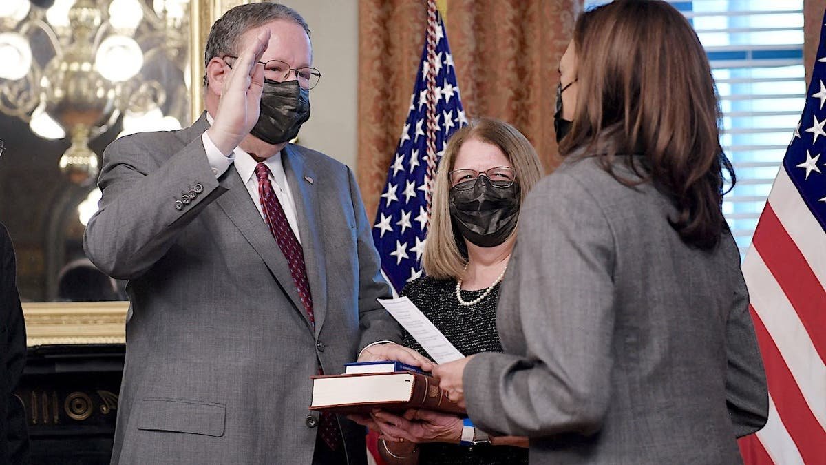 Vice President Kamala Harris swears in David L. Cohen as his wife Rhonda Cohen holds the Bible.