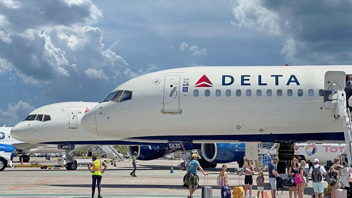 A Delta airplane with passengers outside of it.