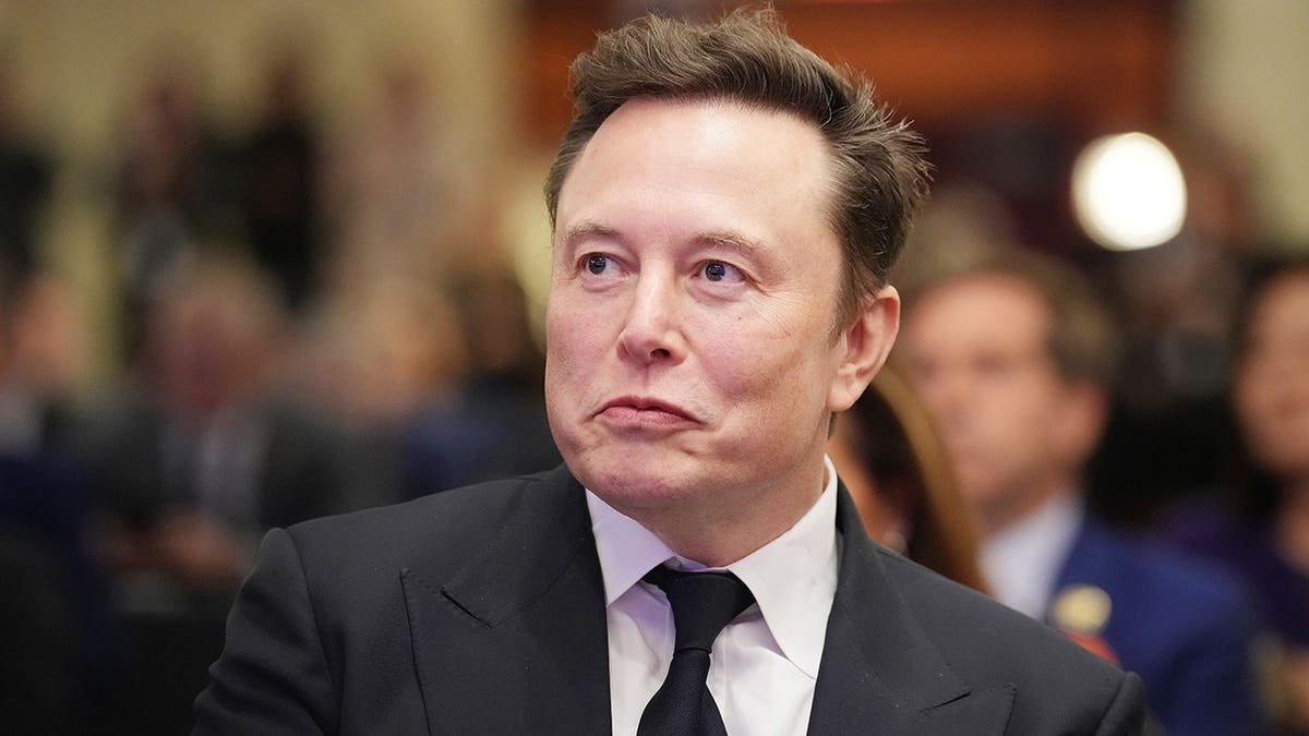 Elon Musk listens as Donald Trump speaks at a House Republicans Conference meeting.