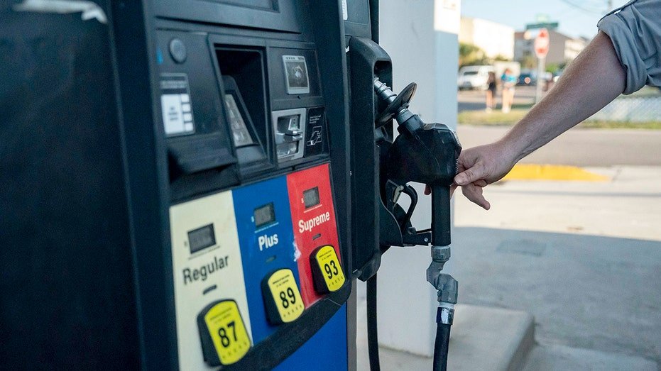 Person reaching for gas pumpp