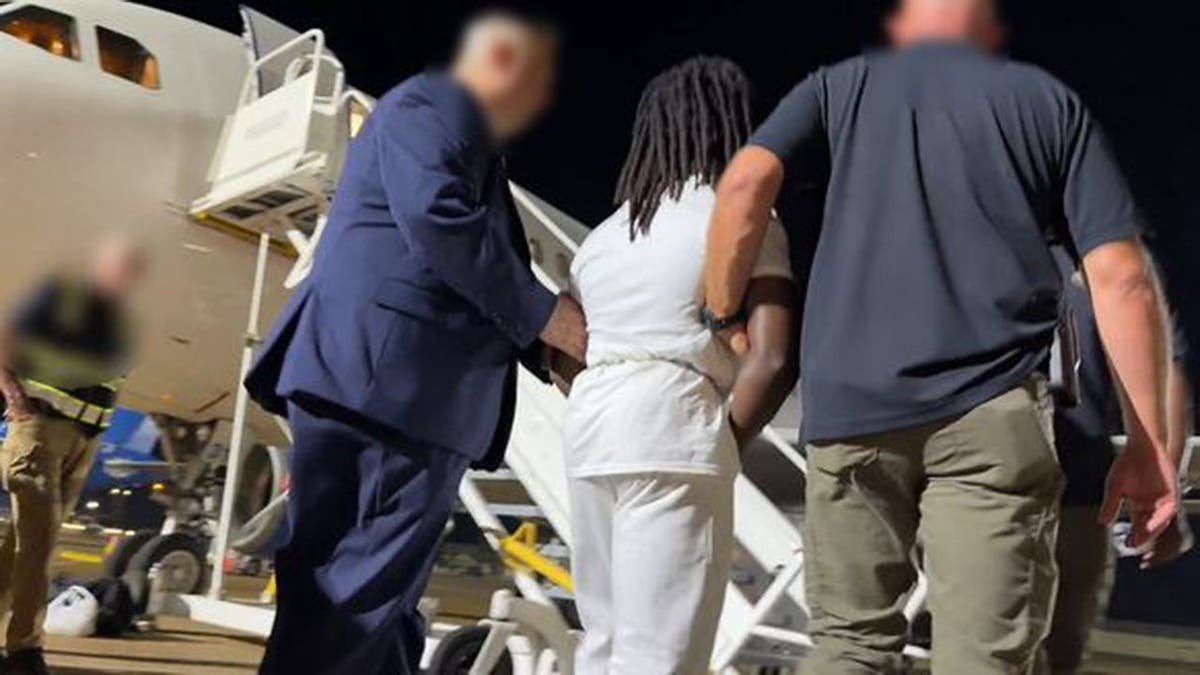 Haitian illegal immigrant Wisteguens Jean Quely Charles is escorted by federal agents to a plane. Charles was deported by ICE.