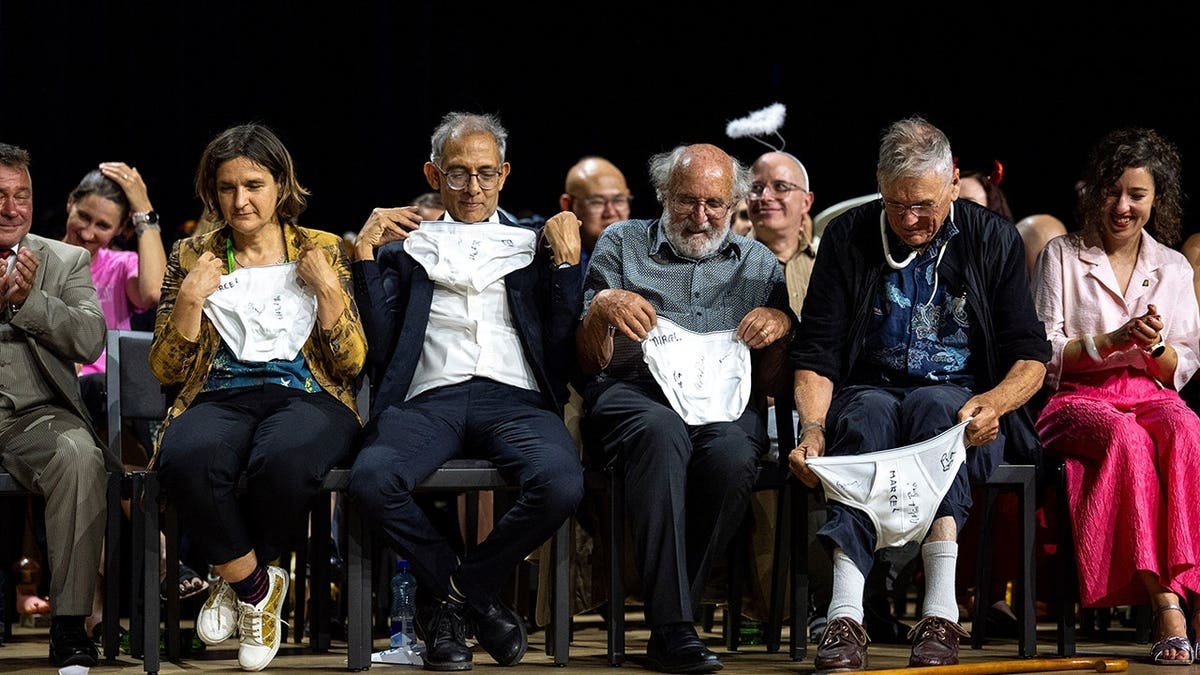 Esther Duflo, Abhijit Banerjee, Michel Mayor and Tim Hunt examine underwear at an awards ceremony.