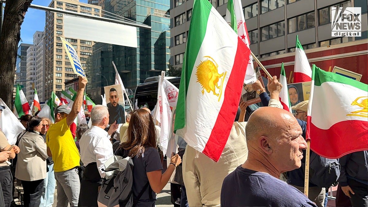 Demonstrators hold signs and flags.