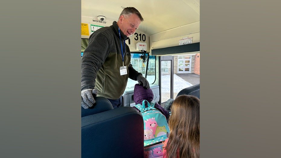 Kurtis Kotes helps students aboard a school bus during a morning route.