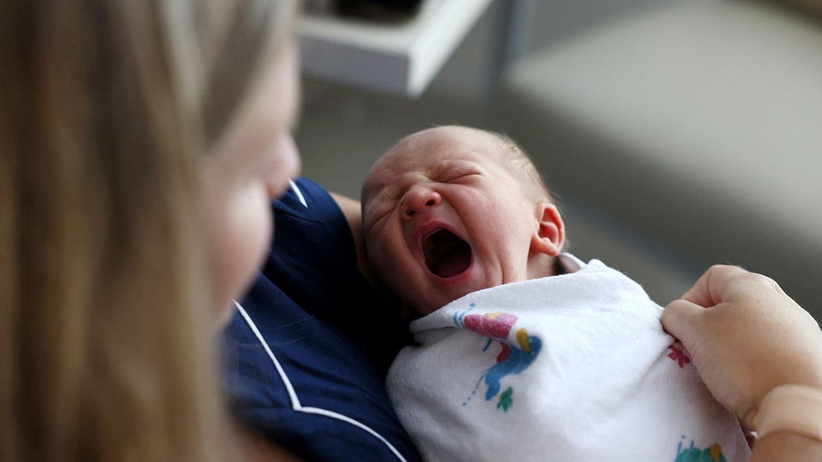 A newborn baby boy yawns as he sits with his mother at Emerson Hospital.