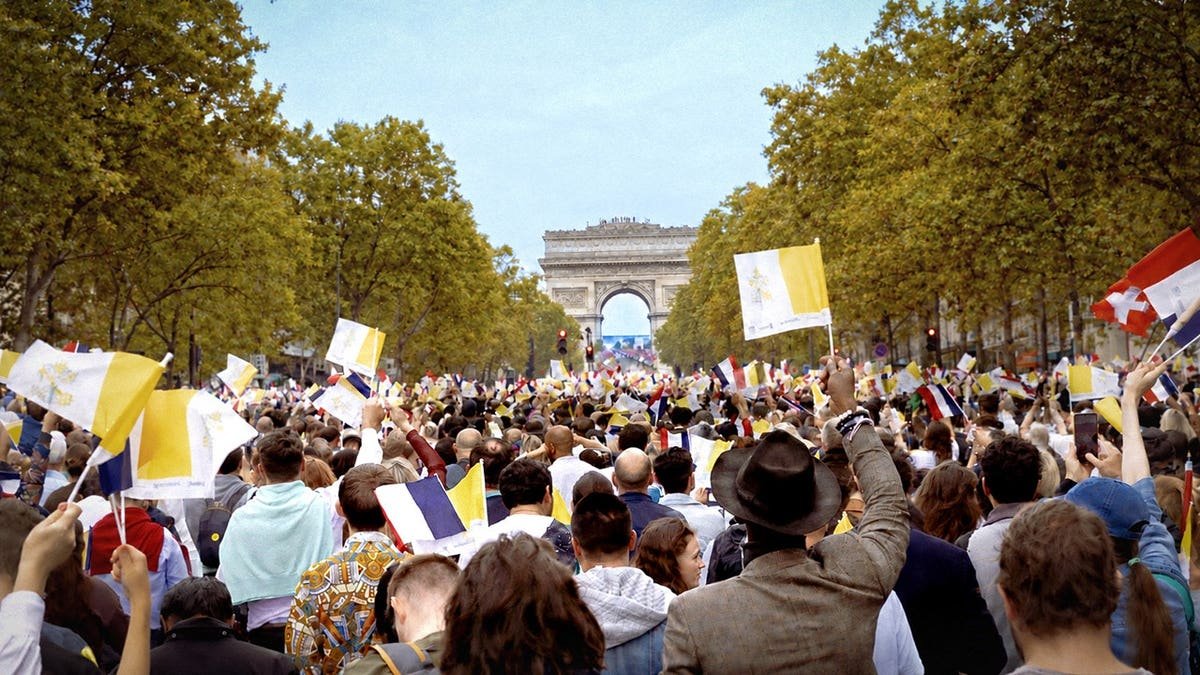 Crowd watches Pope Leo XIV on a giant screen near the Arc de Triomphe in Paris.