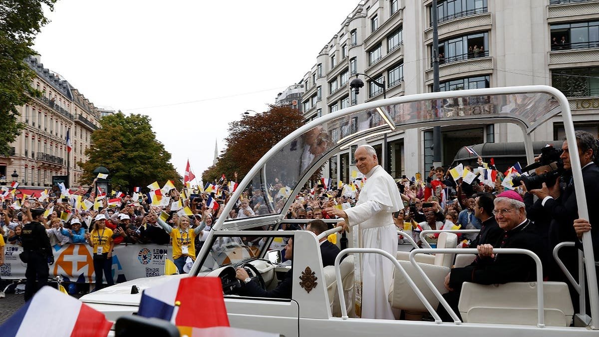 Pope Leo XIV waves from the papamobile on the Champs-Élysées in Paris.