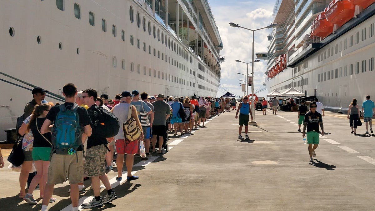 Passengers wait in line to board a cruise ship.