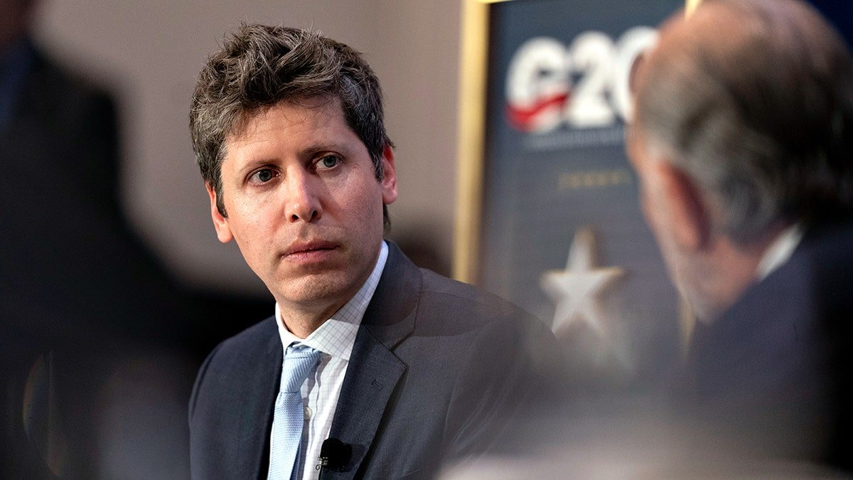 Sam Altman dressed in a suit and tie listening intently