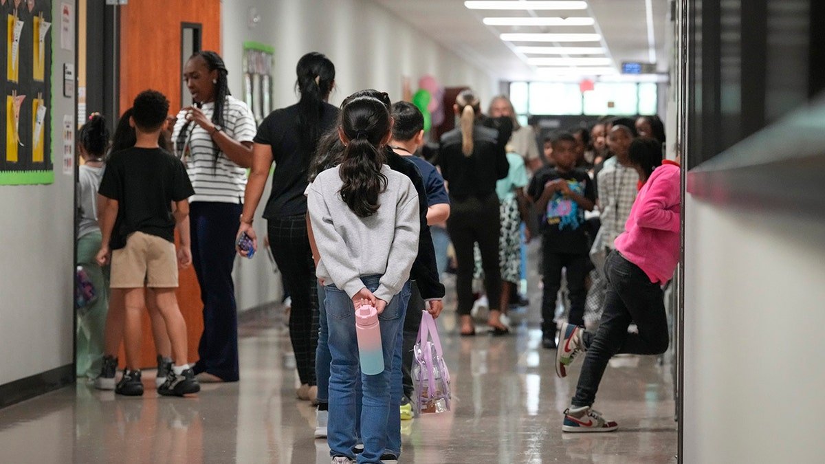 public school students stand in hallway outside classroom