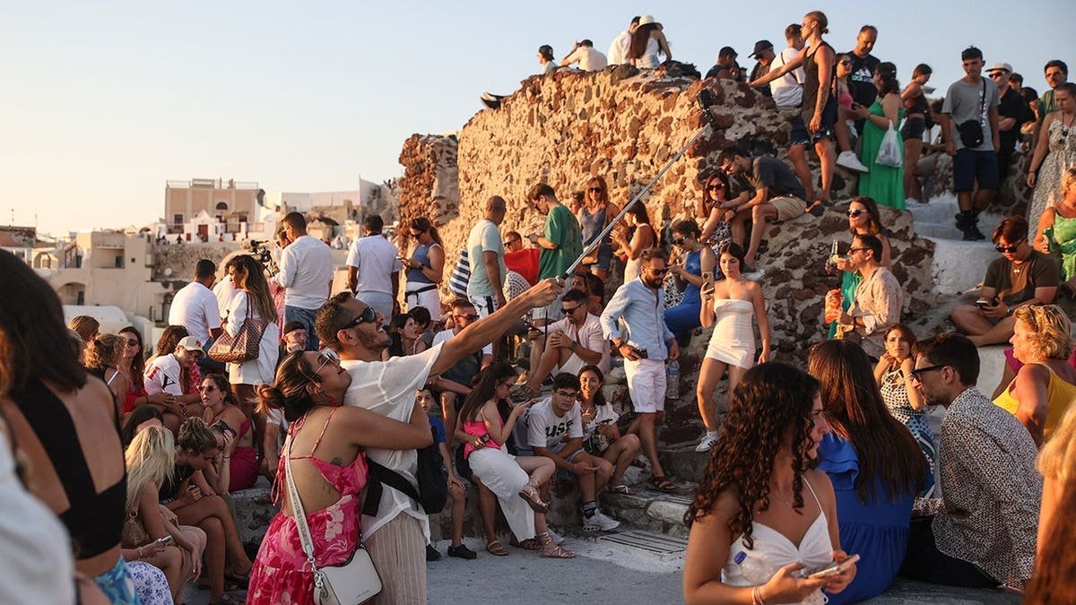 Tourists gather in Oia village as the sun sets over Santorini.
