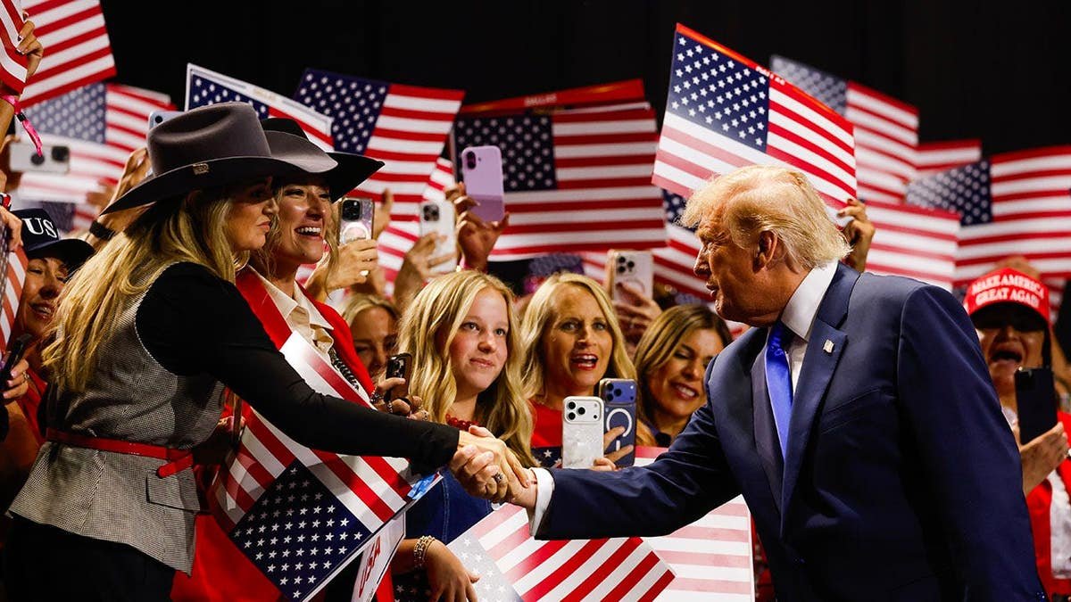 Donald Trump greets attendees while walking on stage at the American Airlines Center in Dallas, Texas.