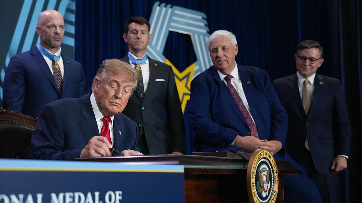 President Donald Trump signs a document at a table during an event in Arlington, Texas.