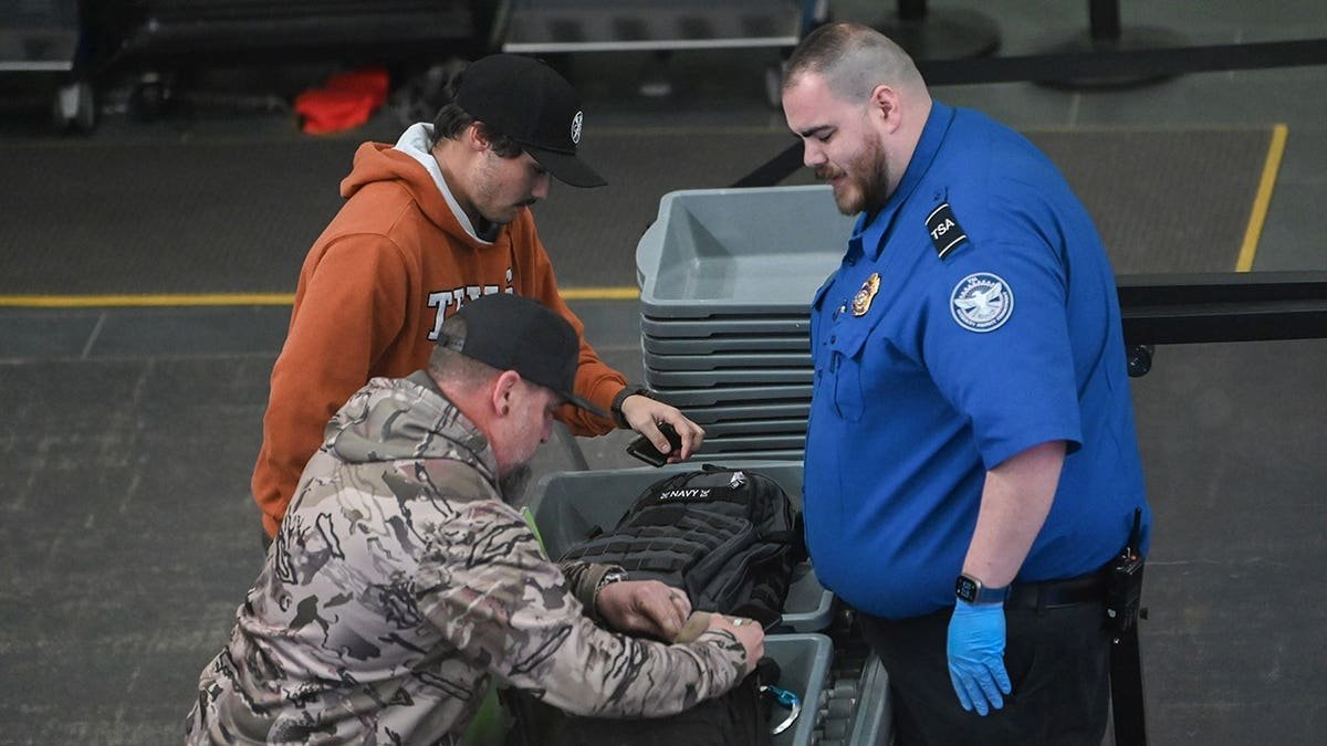TSA worker stands with travelers at security checkpoint at Albany International Airport.