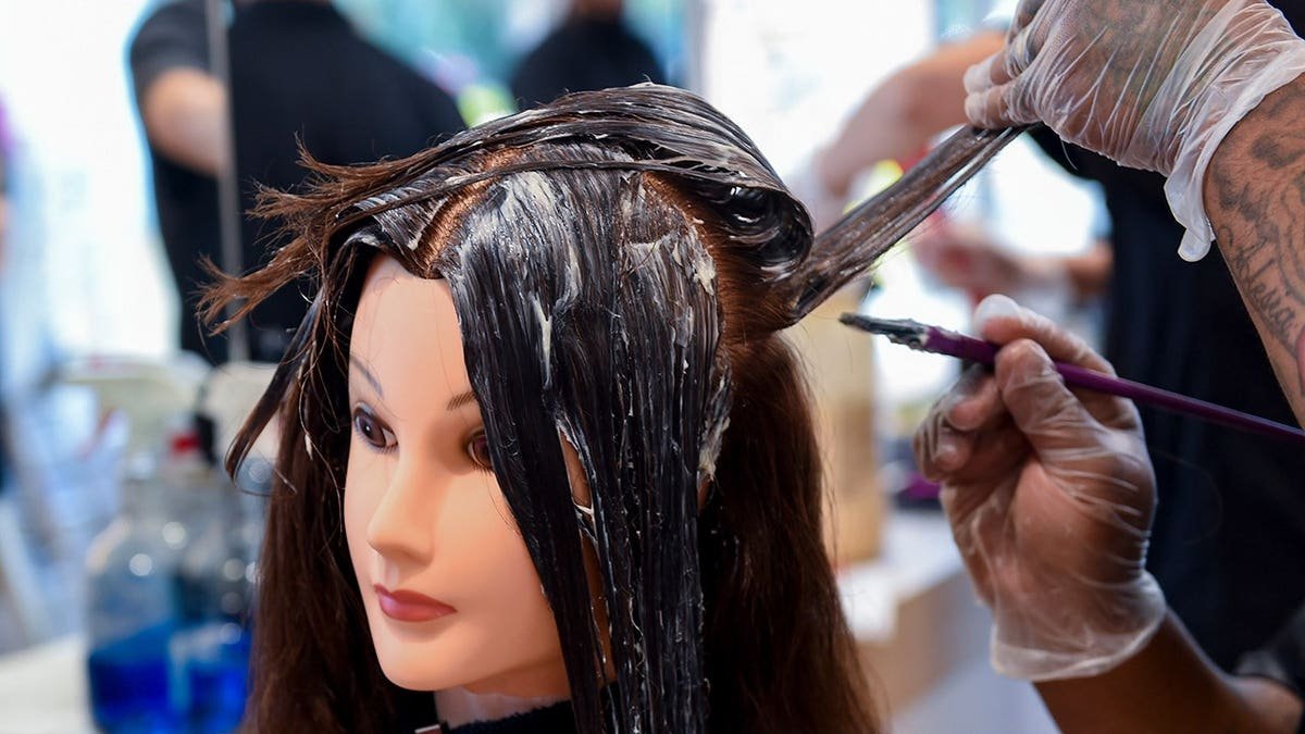 Tyneisha Bell applies color to a mannequin head at a beauty academy.